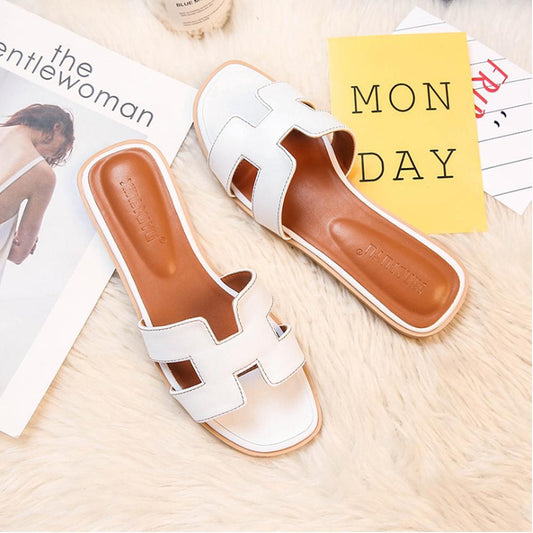 Weiße Damen-Sandalen aus Leder auf Teppich, modisch, bequem, ideal für Sommer.