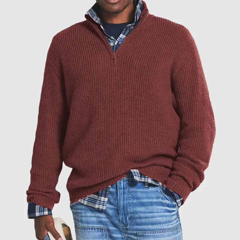 Mann in rotem Strickpullover mit Reißverschluss, kariertem Hemd und blauer Jeans.