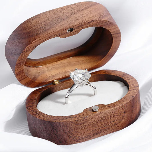 Silberner Verlobungsring mit großem Diamant in eleganter Holzschatulle auf weißem Hintergrund.