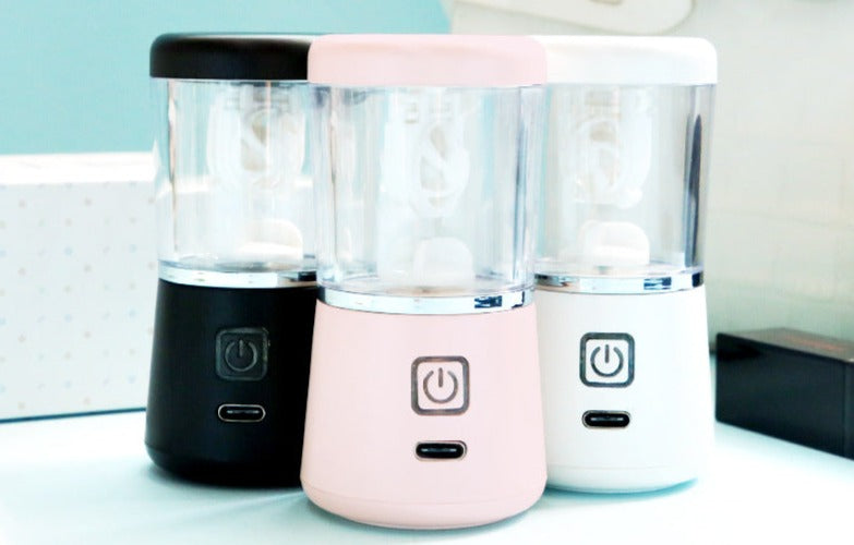 Drei tragbare Mixer in Schwarz, Rosa und Weiß, USB-aufladbar, auf blauem Hintergrund.