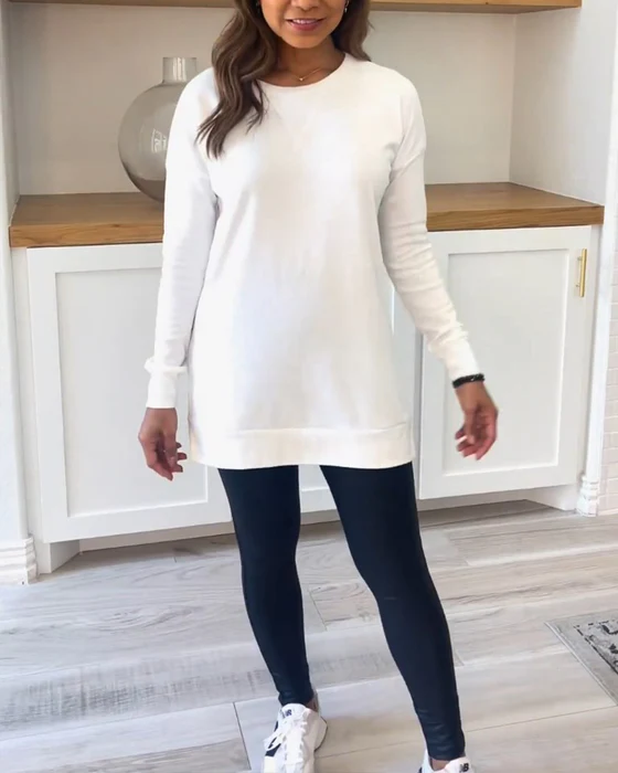 Frau in weißem Pulloverkleid und schwarzen Leggings, lässige Mode, Holzboden, modernes Interieur.