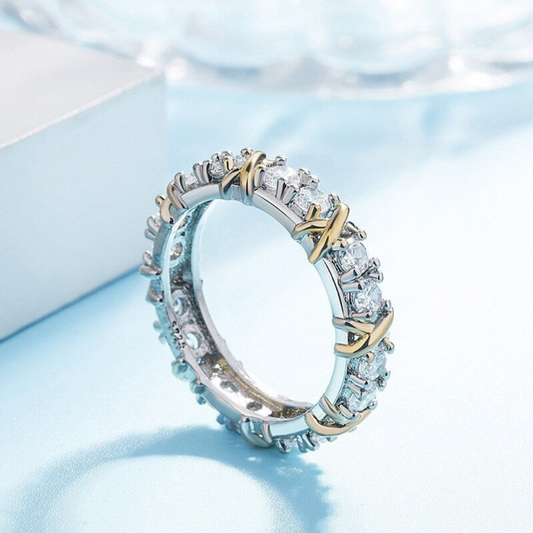 Silberner Ehering mit Diamanten und goldenen Akzenten auf blauem Hintergrund.