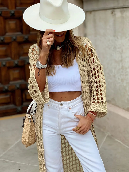 Frau mit weißem Hut, gehäkeltem Cardigan, weißem Top und Hose, modisch, Sommeroutfit.