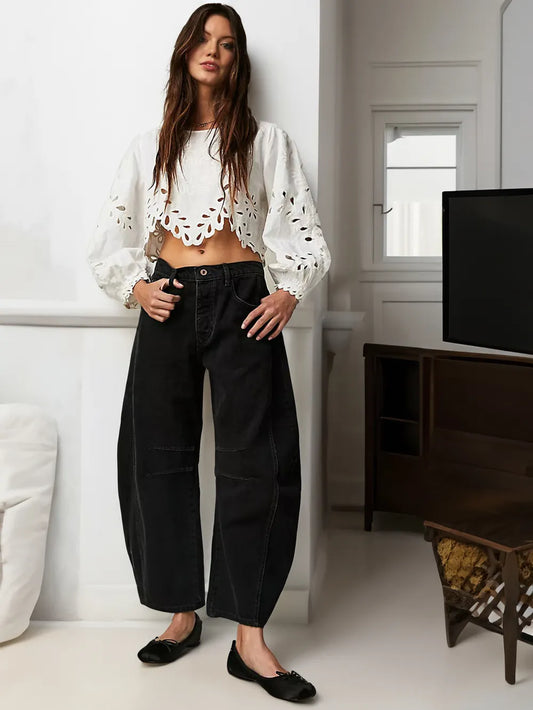Frau in weißer Spitzenbluse und schwarzer Jeans, modisch, lässig, modern, Wohnzimmer.