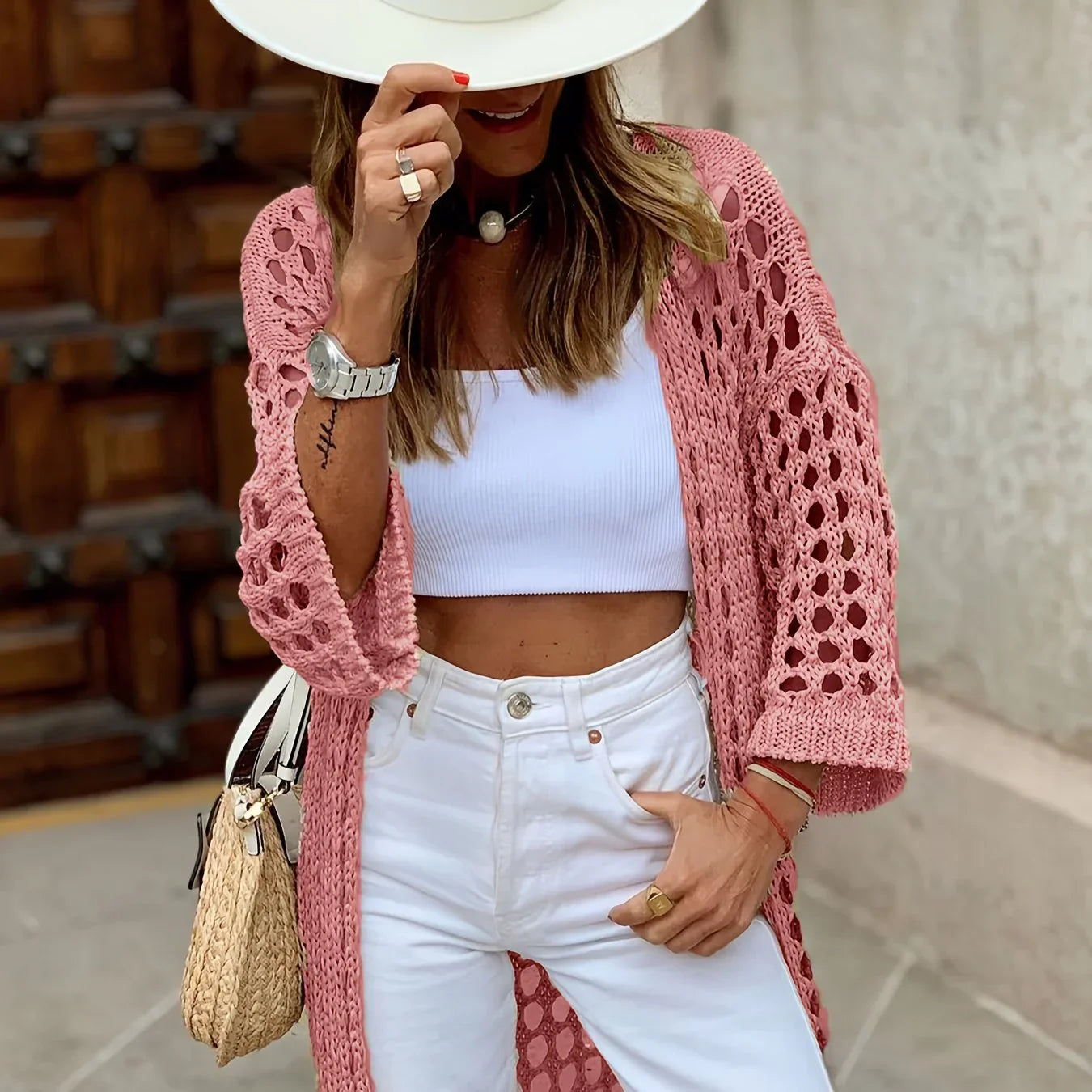 Frau in rosa Strickjacke, weißem Top und Hut, modisch, Sommeroutfit, Accessoires.