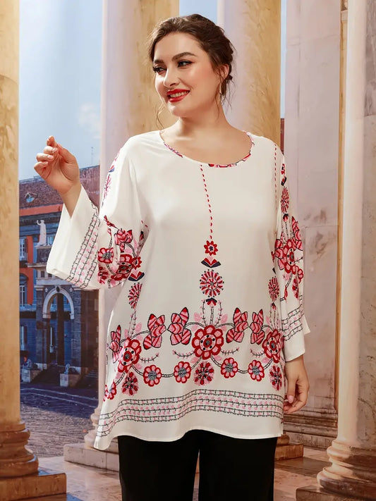 Frau in weißer Bluse mit roten Blumenmustern, lächelnd, vor antiker Architektur.