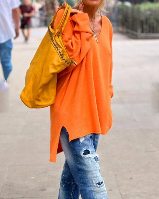 Frau in orangefarbenem Pullover, zerrissene Jeans, gelbe Tasche, Straße, lässige Mode.