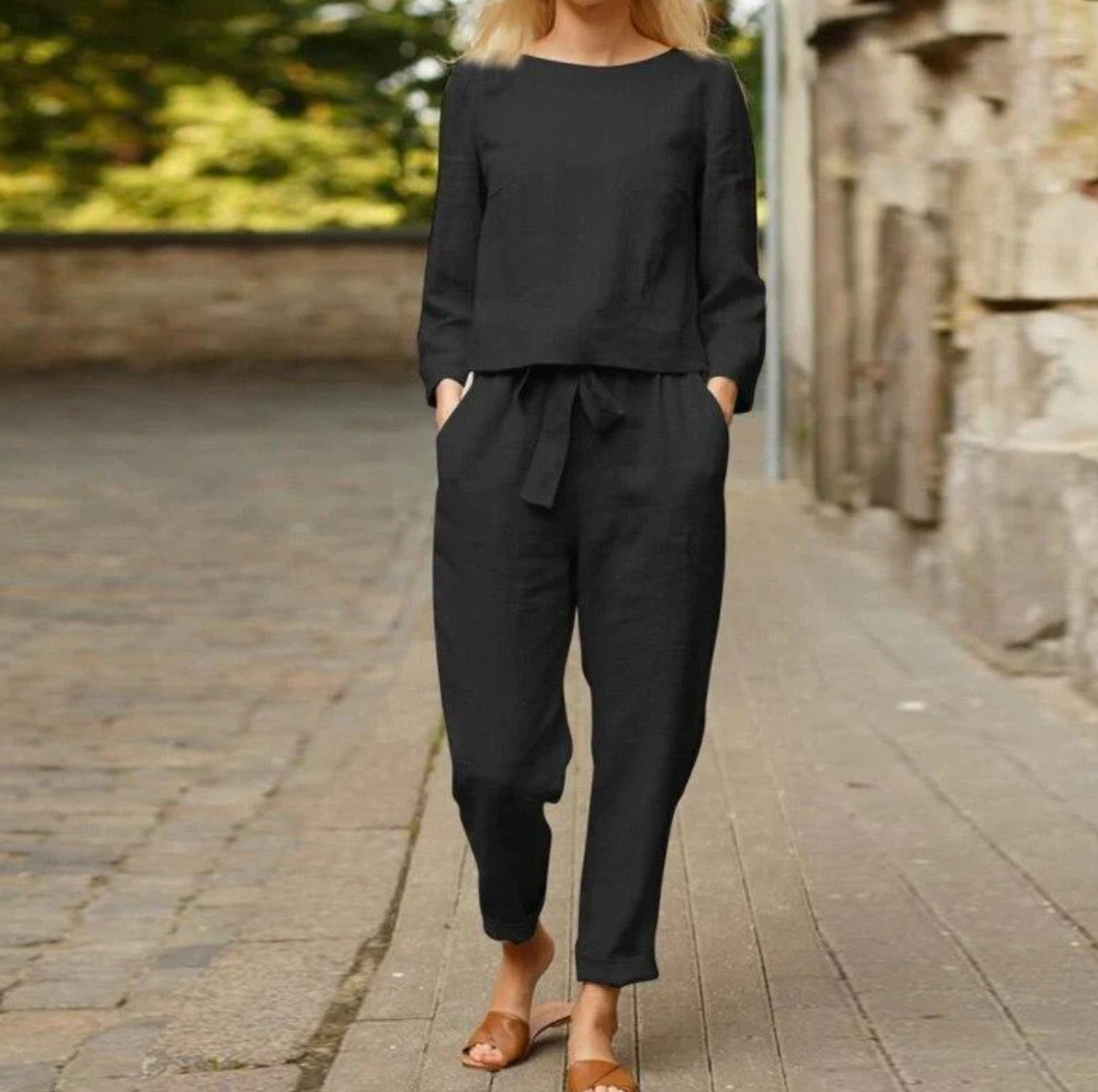 Frau in schwarzem Leinenanzug, lässig, elegant, auf Kopfsteinpflaster, Sommermode.