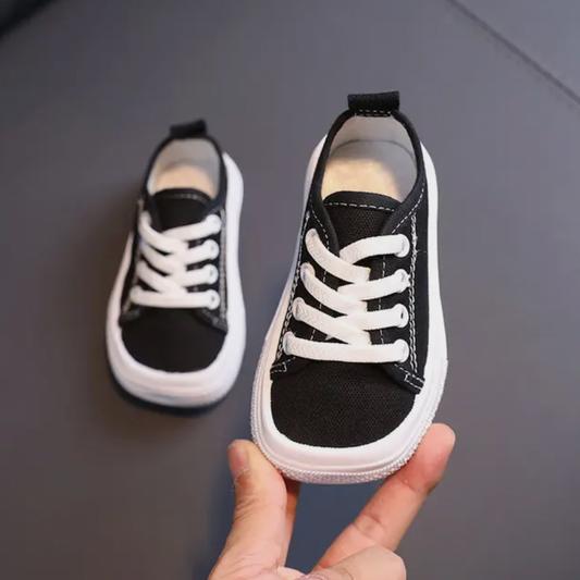 Schwarze Baby-Sneaker mit weißen Schnürsenkeln, rutschfeste Sohle, modische Kinderschuhe.