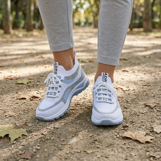 Vit och ljusblå sneaker på en kvinnas fötter, grå leggings, promenad på grusstig med höstlöv i en park. 2
