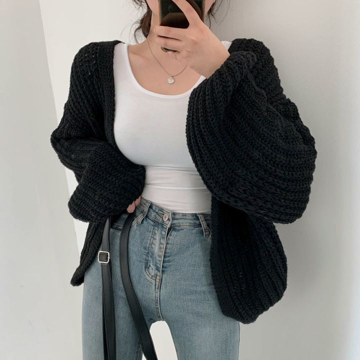 Frau in schwarzer Strickjacke, weißem Top und blauer Jeans, modisch, lässig, Herbstmode.