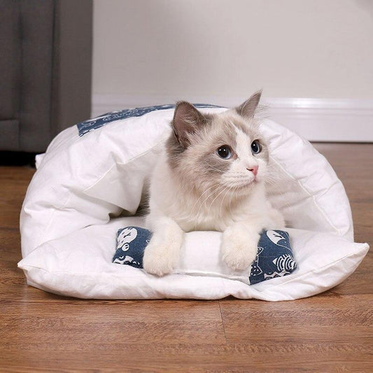 Katze in weißem, blau gemustertem Katzenbett auf Holzboden, gemütlich und entspannt.
