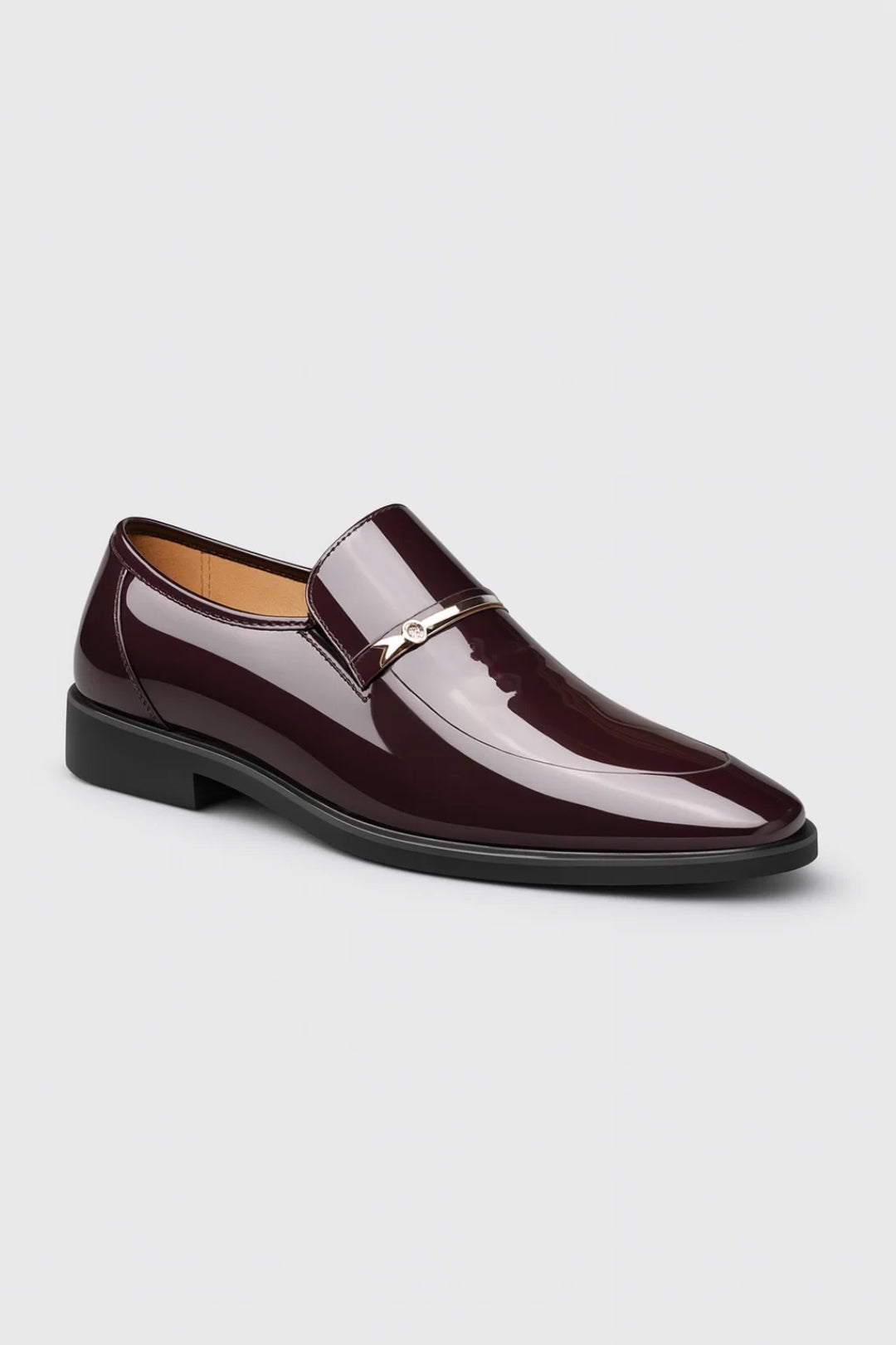 Vinröd blank loafer med smal metalldetalj och liten sten, sedd snett framifrån mot ljus bakgrund 2
