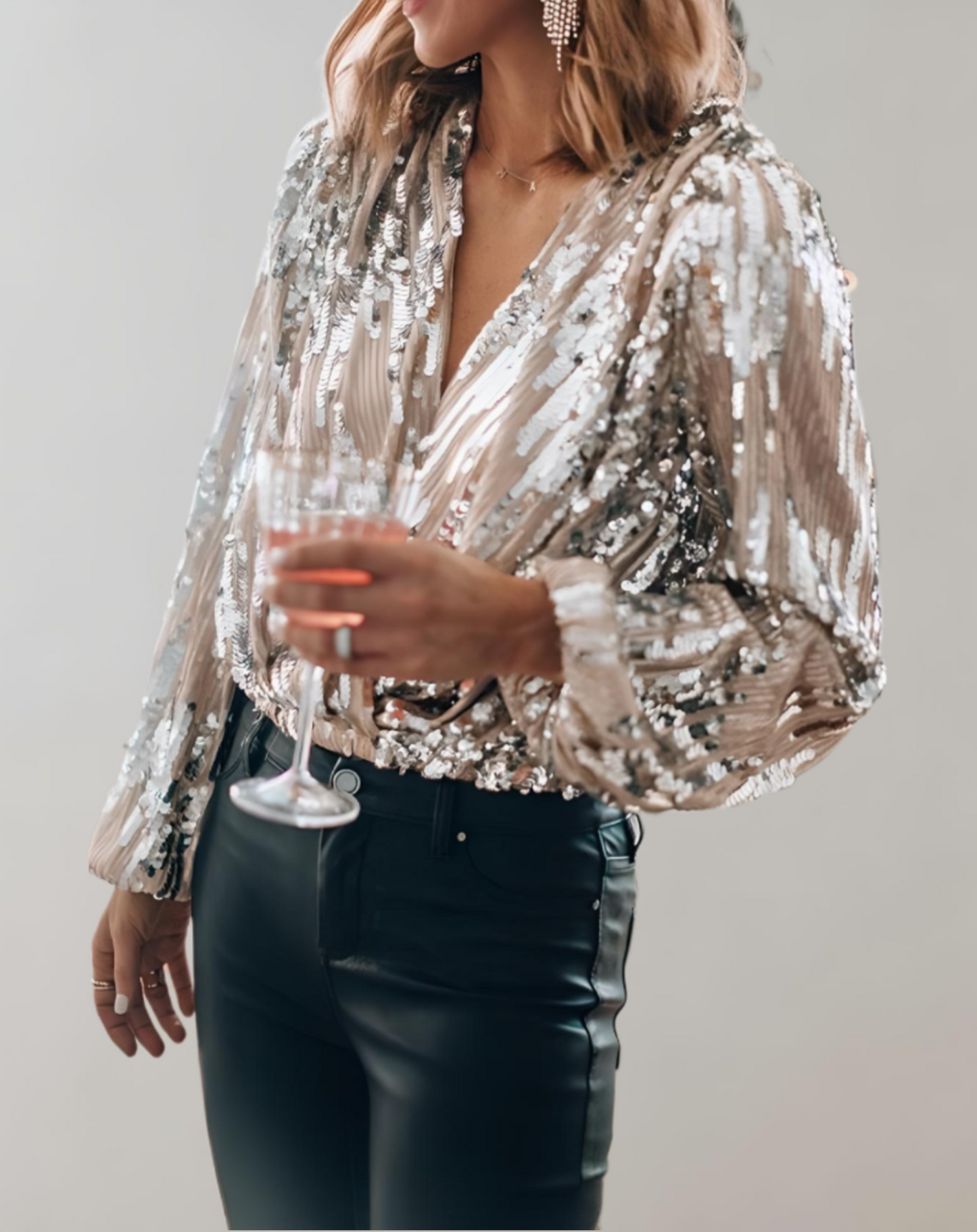 Frau in silberner Paillettenbluse mit Weinglas, elegante Abendmode, Party-Outfit.