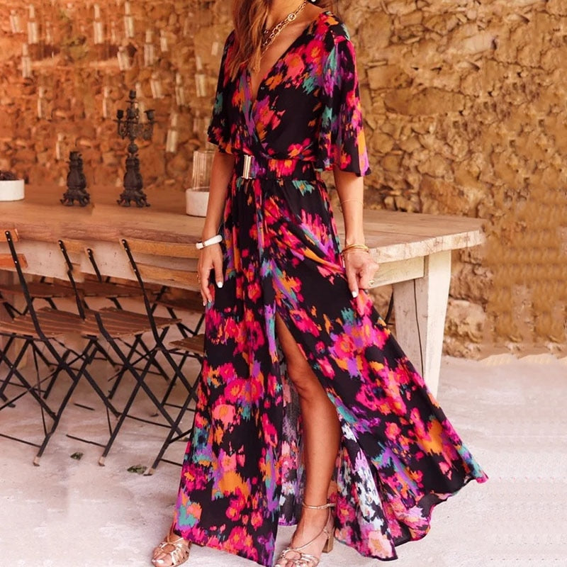 Frau in bunter Maxi-Wickelkleid, Blumenmuster, vor rustikalem Holztisch, Sommermode.