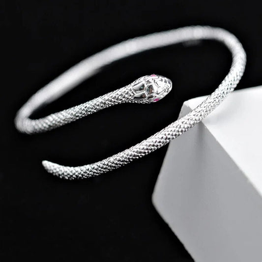 Silbernes Schlangenarmband, offenes Design, strukturiert, eleganter Schmuck auf schwarzem Hintergrund.