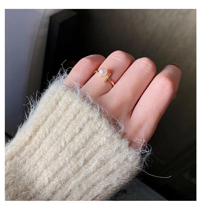 Hand mit goldfarbenem Perlenring, Strickpullover, eleganter Schmuck, Damenmode.