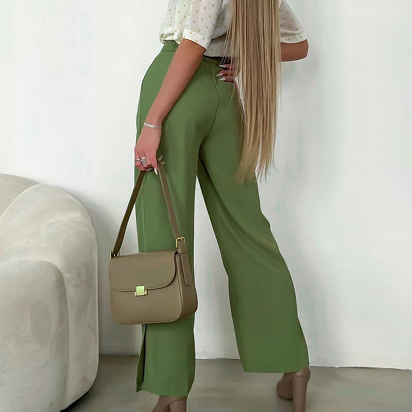 Grüne Damenhose mit weitem Bein, elegantes Design, kombiniert mit beiger Handtasche.