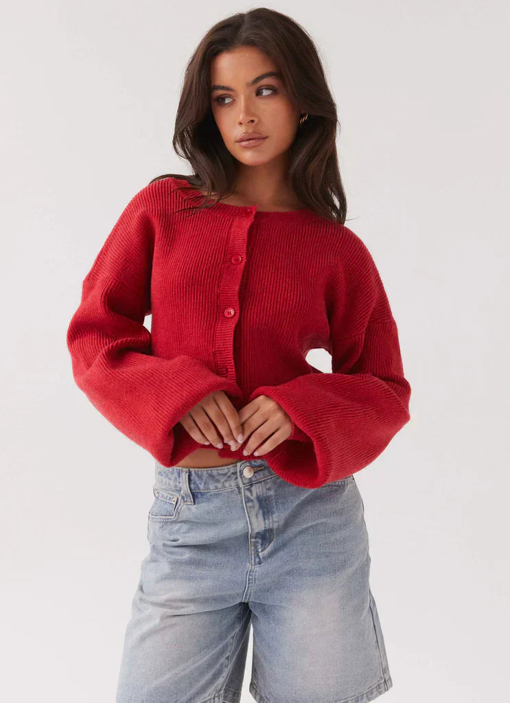 Frau trägt roten Strick-Cardigan und Jeansshorts, modische Damenbekleidung, lässiger Stil.