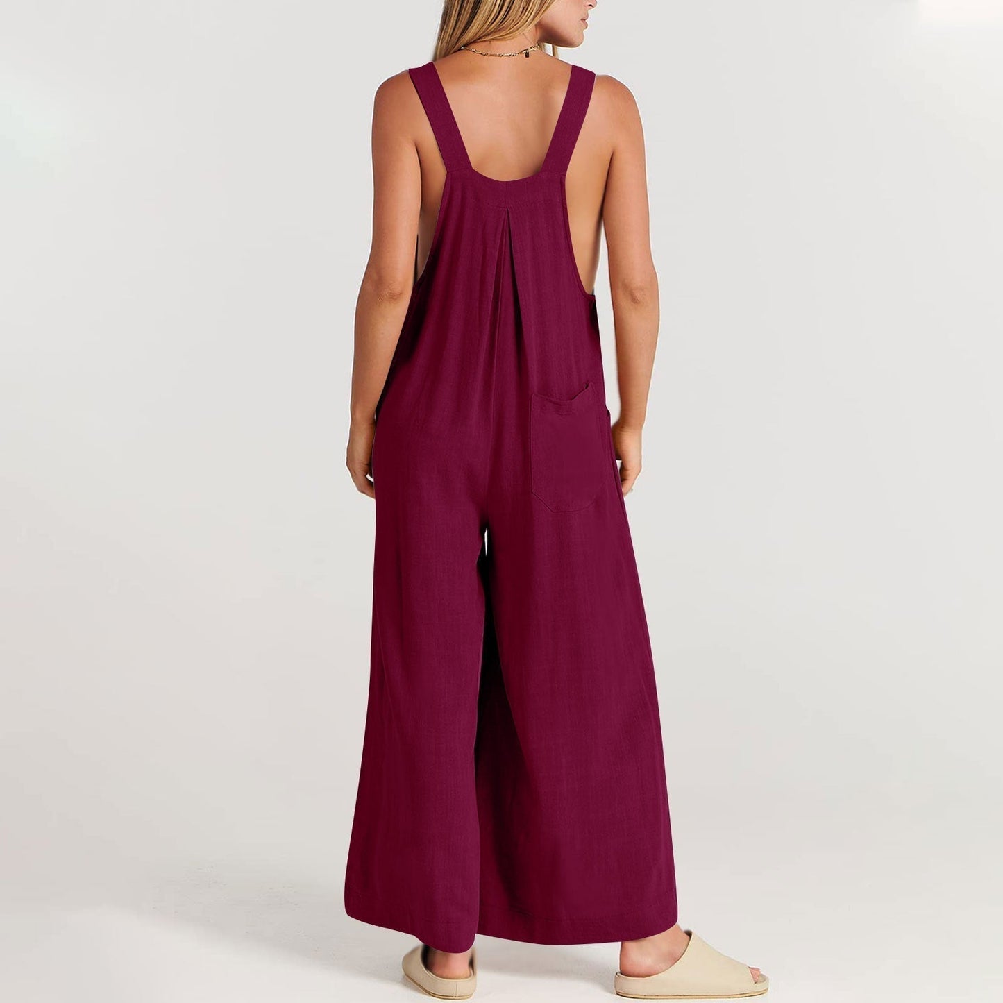 Frau in weinrotem Jumpsuit aus Leinen, Rückansicht, lässige Sommermode, barfuß.