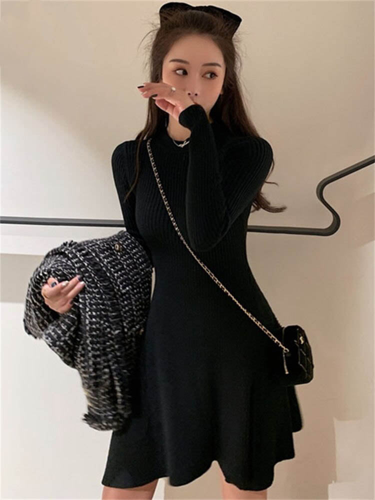 Frau in schwarzem Strickkleid mit Handtasche, hält karierten Schal, modisch, elegant.