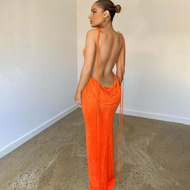 Frau in orangefarbenem, rückenfreiem Abendkleid, elegantes Design, minimalistischer Raum.