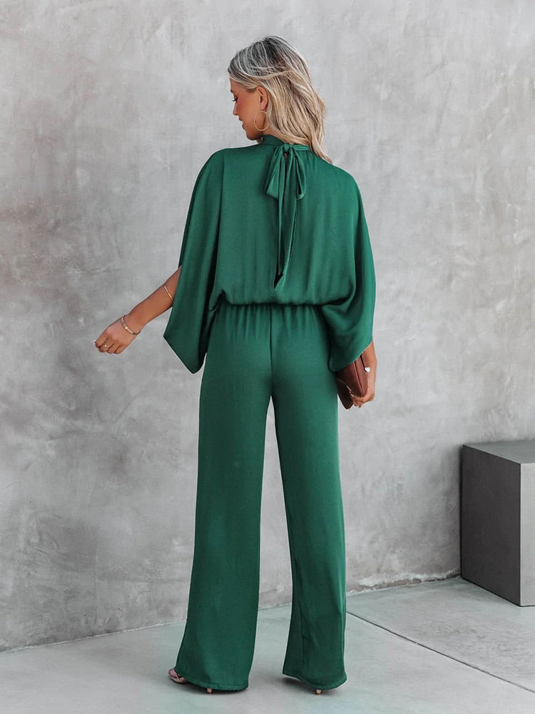Frau in grünem Jumpsuit mit Rückenausschnitt, elegantes Design, modische Damenbekleidung.