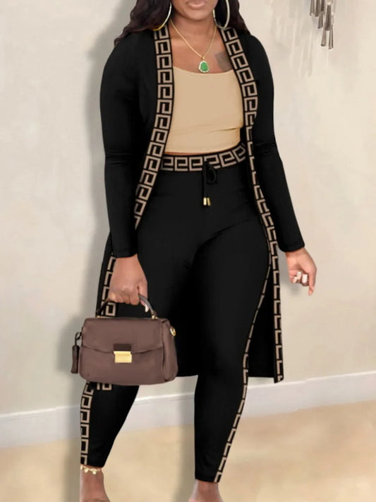 Frau in schwarzem Zweiteiler mit griechischem Muster, braune Handtasche, elegantes Outfit.