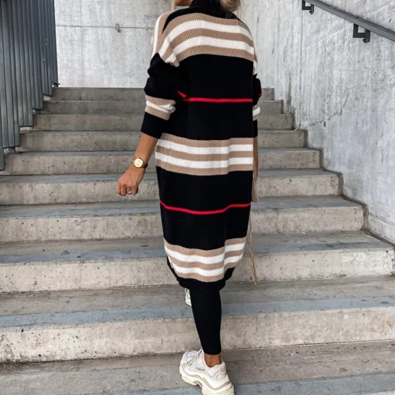 Frau in gestreiftem Strickkleid, schwarz-beige, auf Treppe, modisch, Herbstmode, Sneakers.