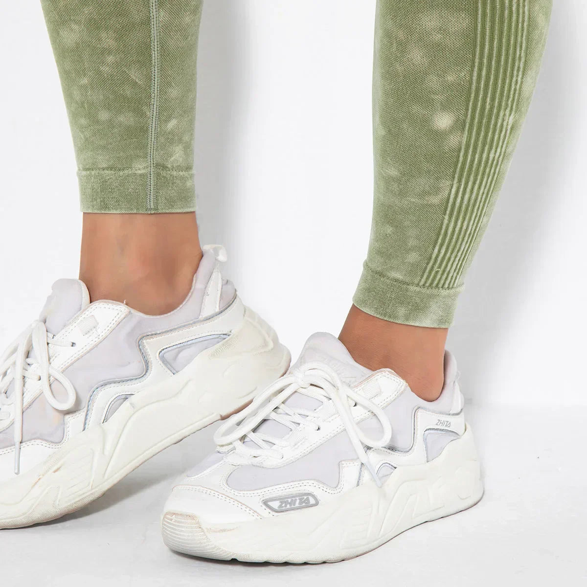 Weiße Sneaker Damen, sportlich, mit grüner Leggings, bequem, modisch, Freizeitkleidung.