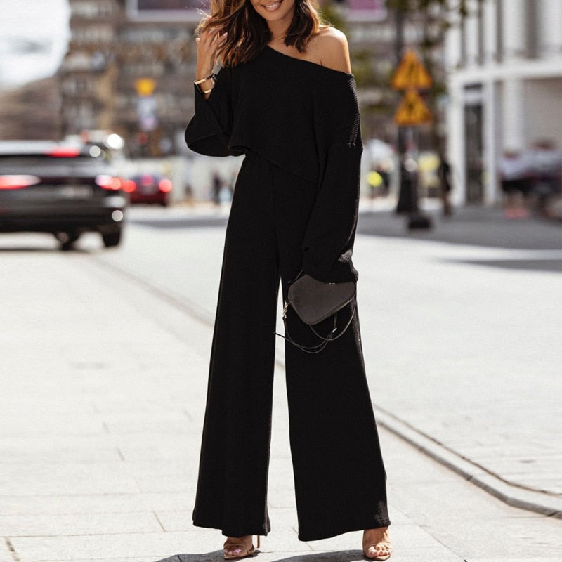 Frau in schwarzem, schulterfreiem Jumpsuit auf Straße, modisch, elegant, urbaner Stil.