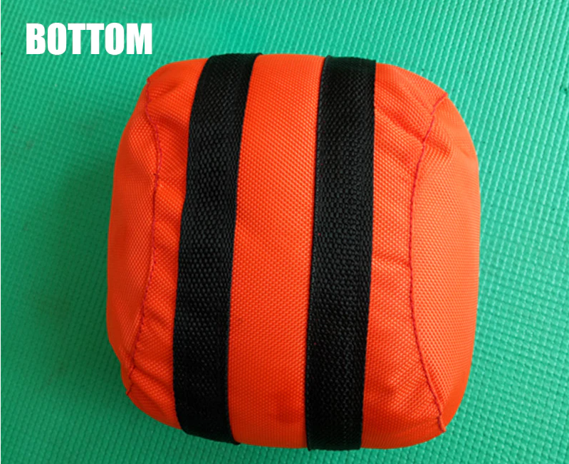 Orangefarbener Sandsack mit schwarzen Streifen auf grünem Hintergrund, Fitnesszubehör.