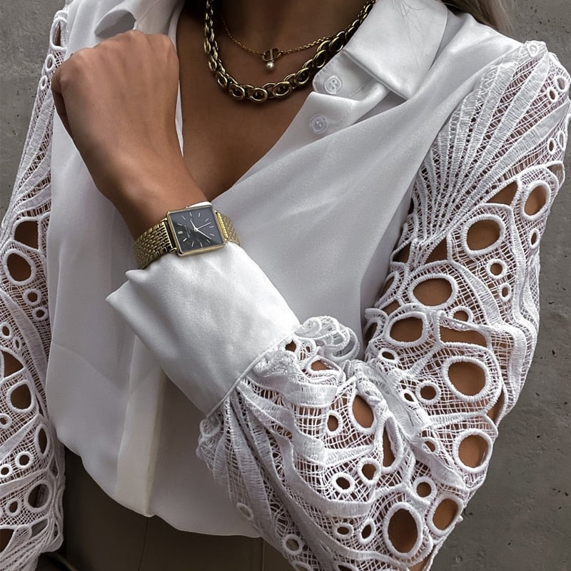 Frau in weißer Spitzenbluse mit goldener Uhr und Kette, elegantes Modeaccessoire.