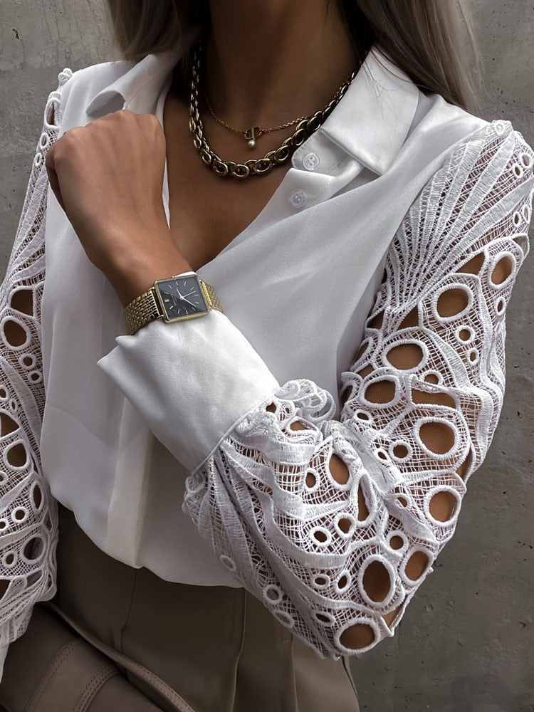 Frau in weißer Bluse mit Spitzenärmeln, goldener Uhr und Kette, eleganter Look.