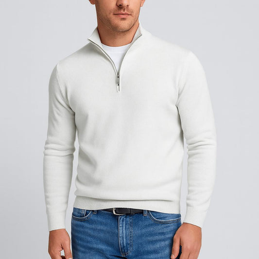Man i vit stickad tröja med halv dragkedja och stående krage, kombinerad med jeans och svart skärp. 2