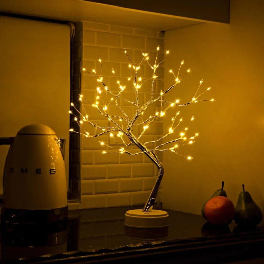 Tänd trädlampa i ett kök framför kakelvägg, bredvid en vattenkokare och några frukter 5