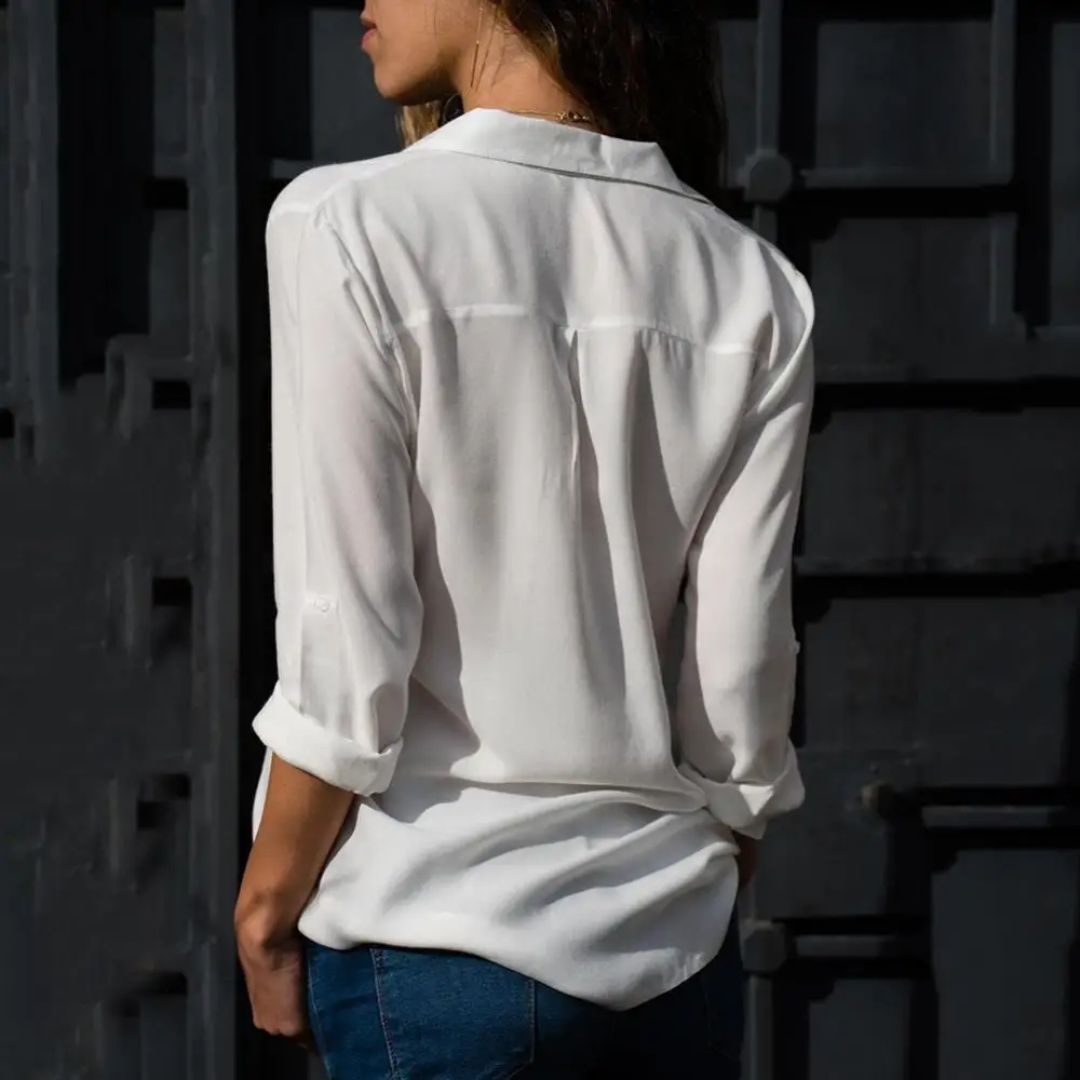 Frau in weißer Bluse und blauer Jeans, Rückansicht, lässige Mode, urbaner Hintergrund.