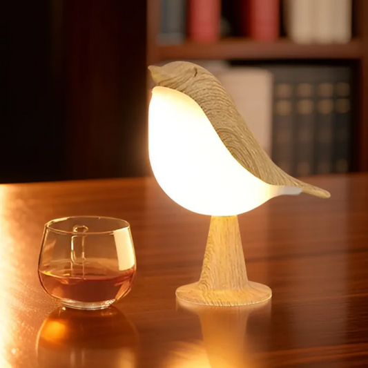 Holz-Vogel-Tischlampe mit warmem Licht neben Glas auf Holztisch, dekorative Beleuchtung.