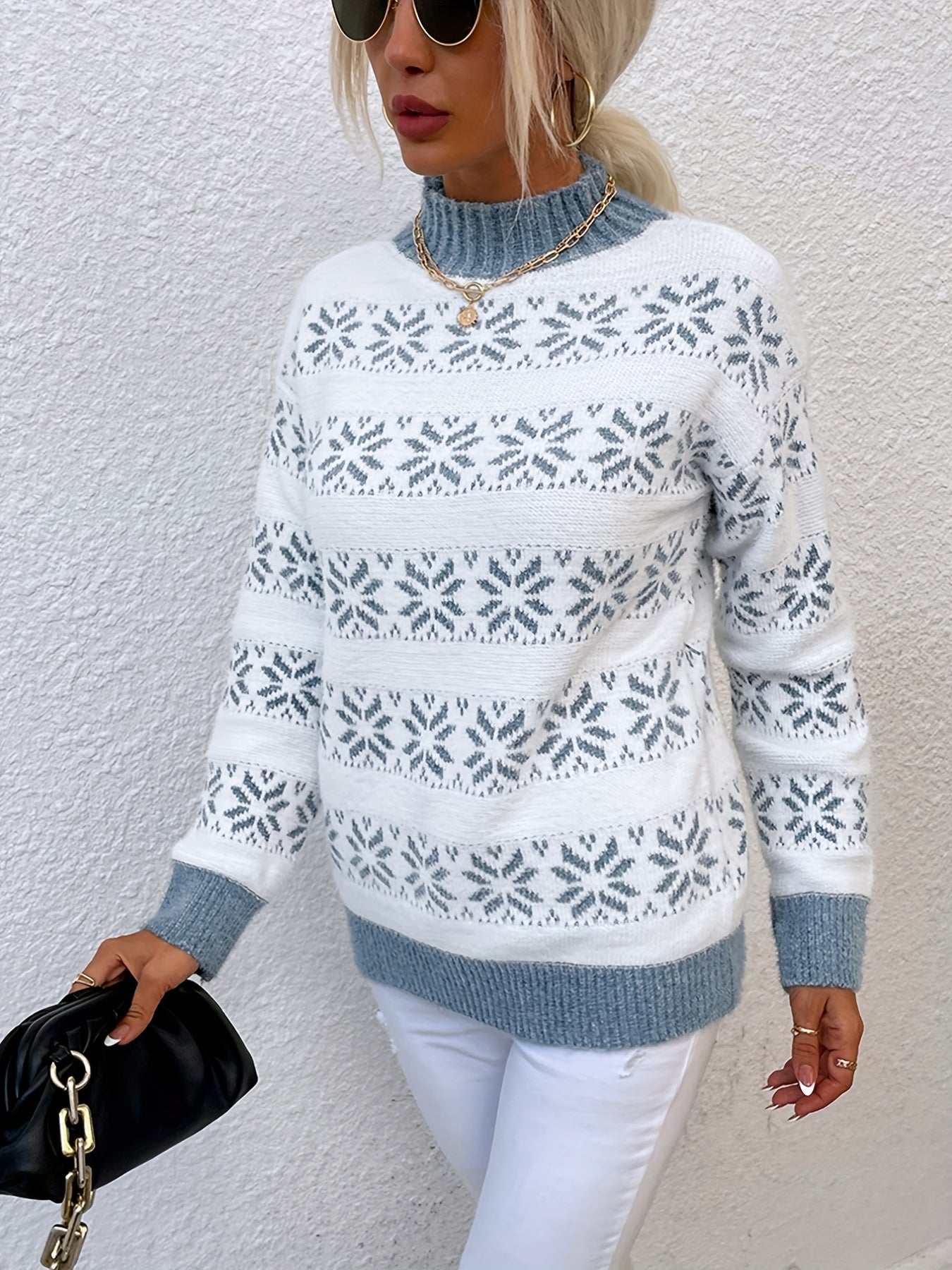 Frau in weiß-blauem Norwegerpullover, Sonnenbrille, weiße Hose, schwarze Tasche.
