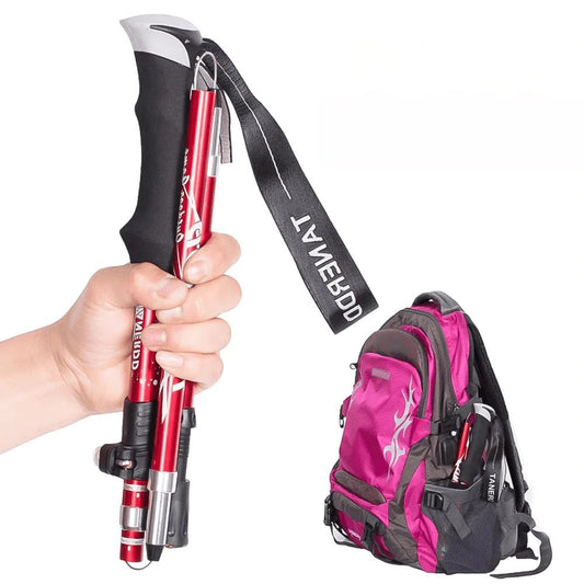 Faltbare, verstellbare Trekkingstöcke, rot, mit ergonomischem Griff, neben pinkem Rucksack.
