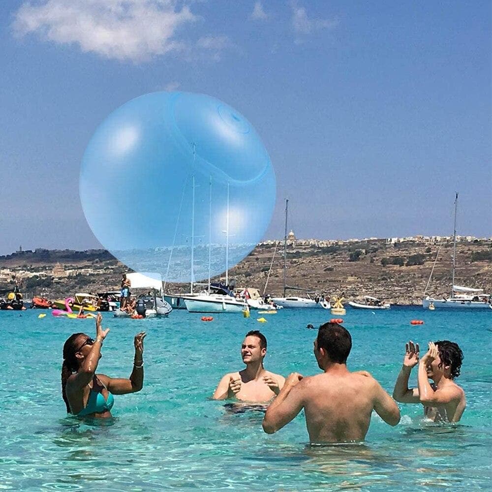 Vier Personen spielen im Wasser mit einem großen blauen aufblasbaren Ball.