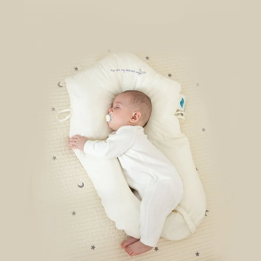 Baby schläft in weißem Babynest auf beigem Hintergrund mit Sternenmuster.