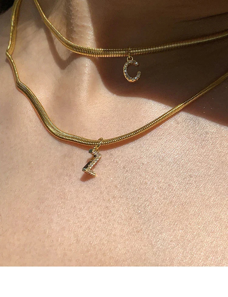Goldene Halsketten mit Buchstabenanhängern, Z und C, auf Haut, modischer Schmuck.