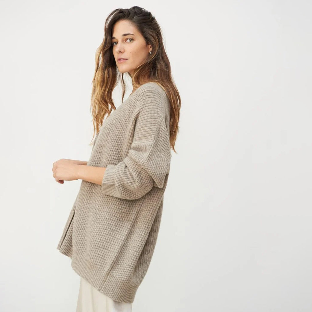 Frau in beigem Strickpullover, lässig, modisch, Herbstmode, Damenbekleidung, neutraler Hintergrund.