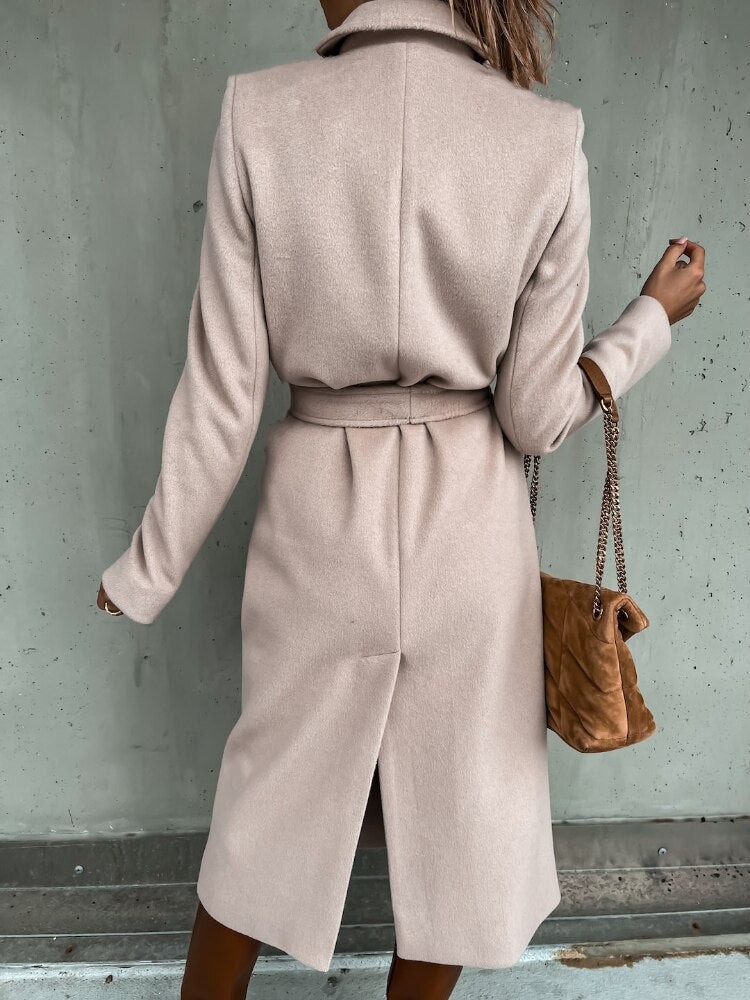 Frau in beigem Wollmantel mit Gürtel, braune Handtasche, eleganter Herbstlook.