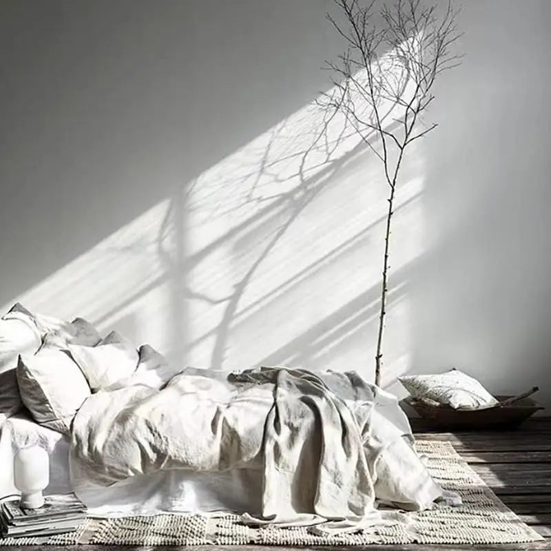 Minimalistisches Schlafzimmer mit weißer Bettwäsche, Holzboden und dekorativem Ast.
