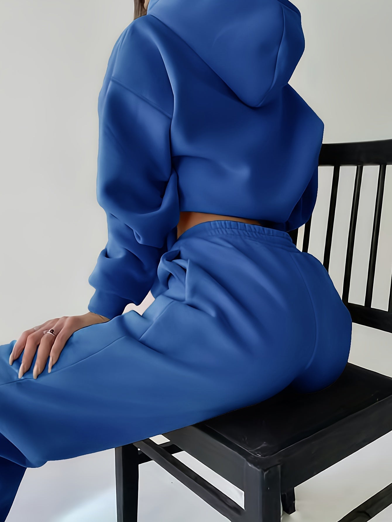 Frau in blauem Jogginganzug auf Stuhl, Freizeitmode, bequeme Kleidung, Sportbekleidung.