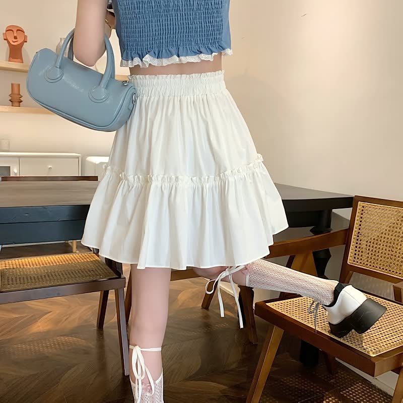 Frau in weißem Rock und blauem Top mit blauer Handtasche, modisch, elegant, Sommeroutfit.