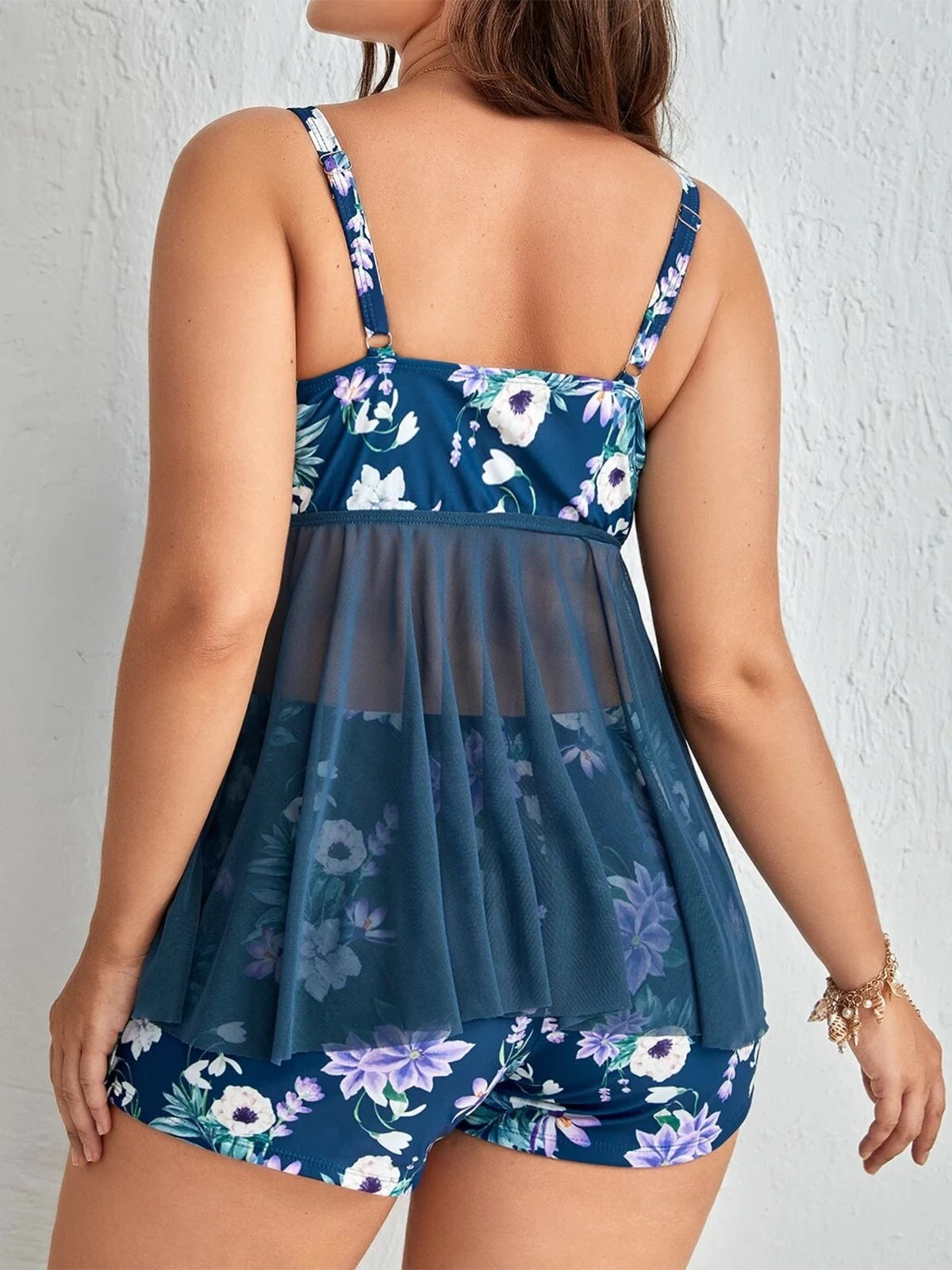 Frau in blauem, geblümtem Tankini-Set mit transparentem Rücken, Sommermode, Bademode.