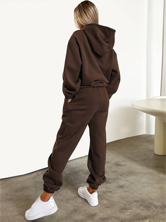 Frau in braunem Hoodie und Jogginghose, weiße Sneaker, lässige Mode, Streetwear-Outfit.